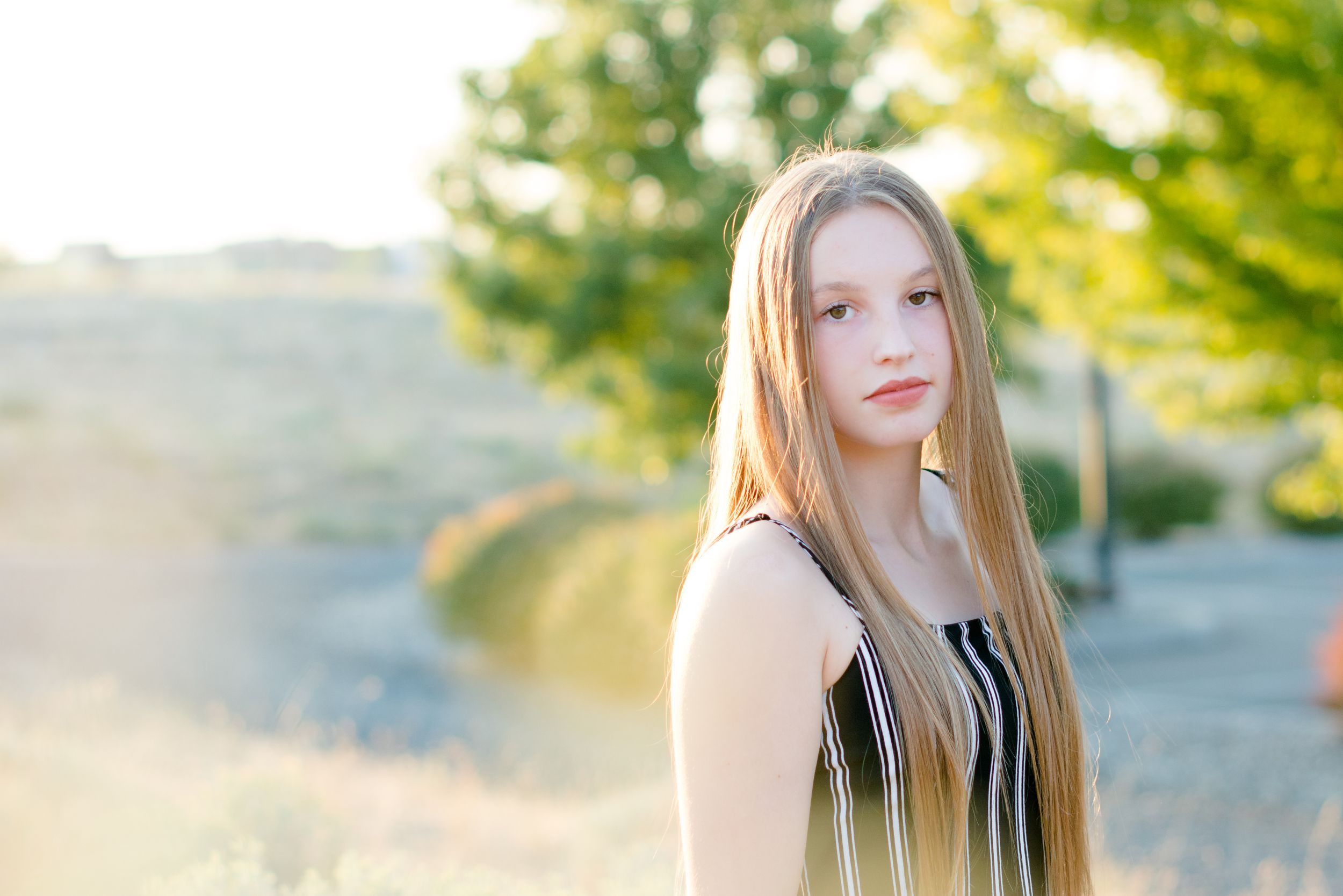 A sun-lit outdoor portrait with natural bokeh and soft lighting effects.
