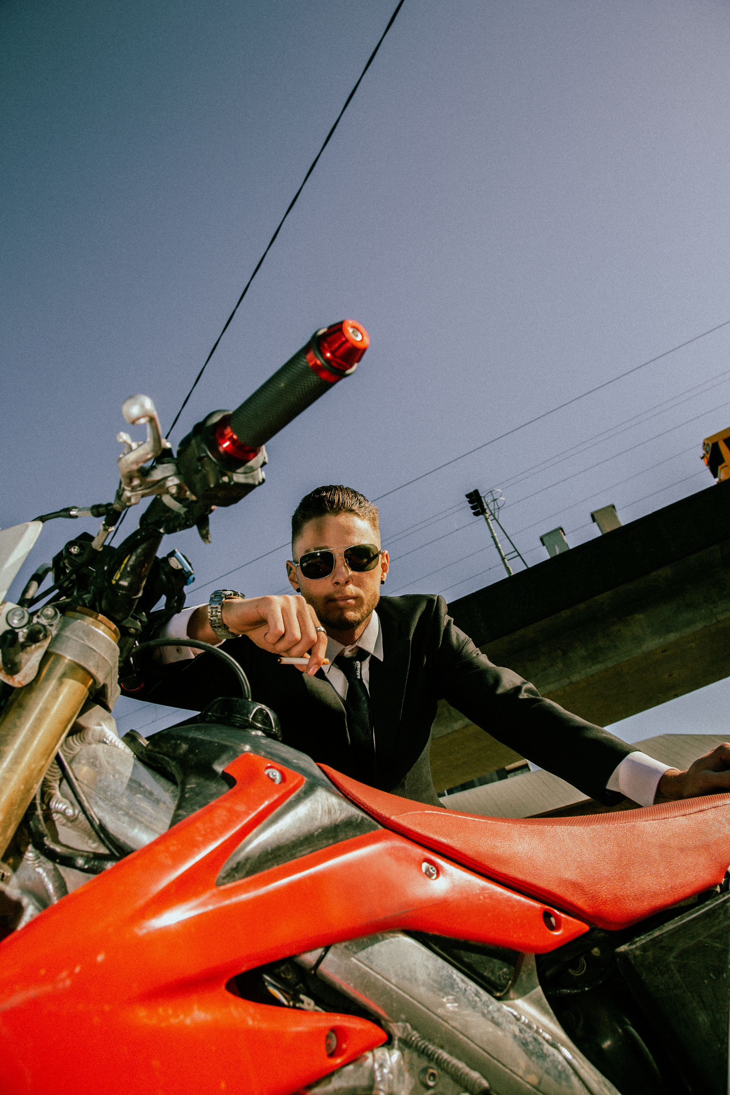 A person in sunglasses riding a red motorcycle shown in a sequence of progressive close-up shots against a cloudy sky.