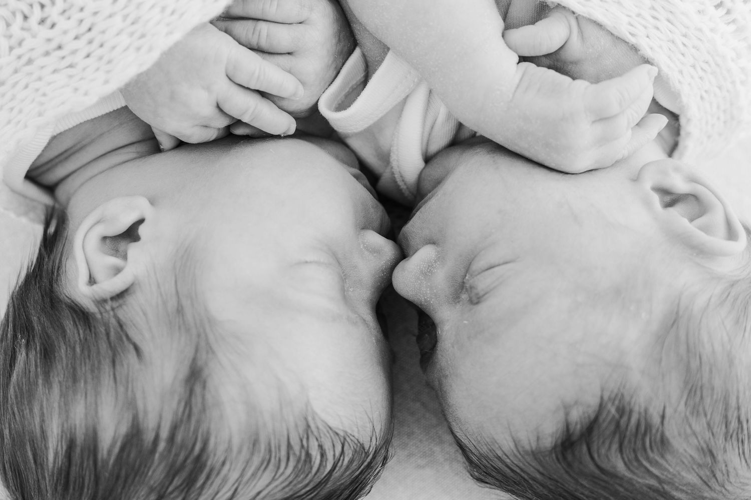 Twin babies peacefully asleep in white swaddle together, photographed by Nottingham newborn photographer at our Nottingham Mapperley studio.