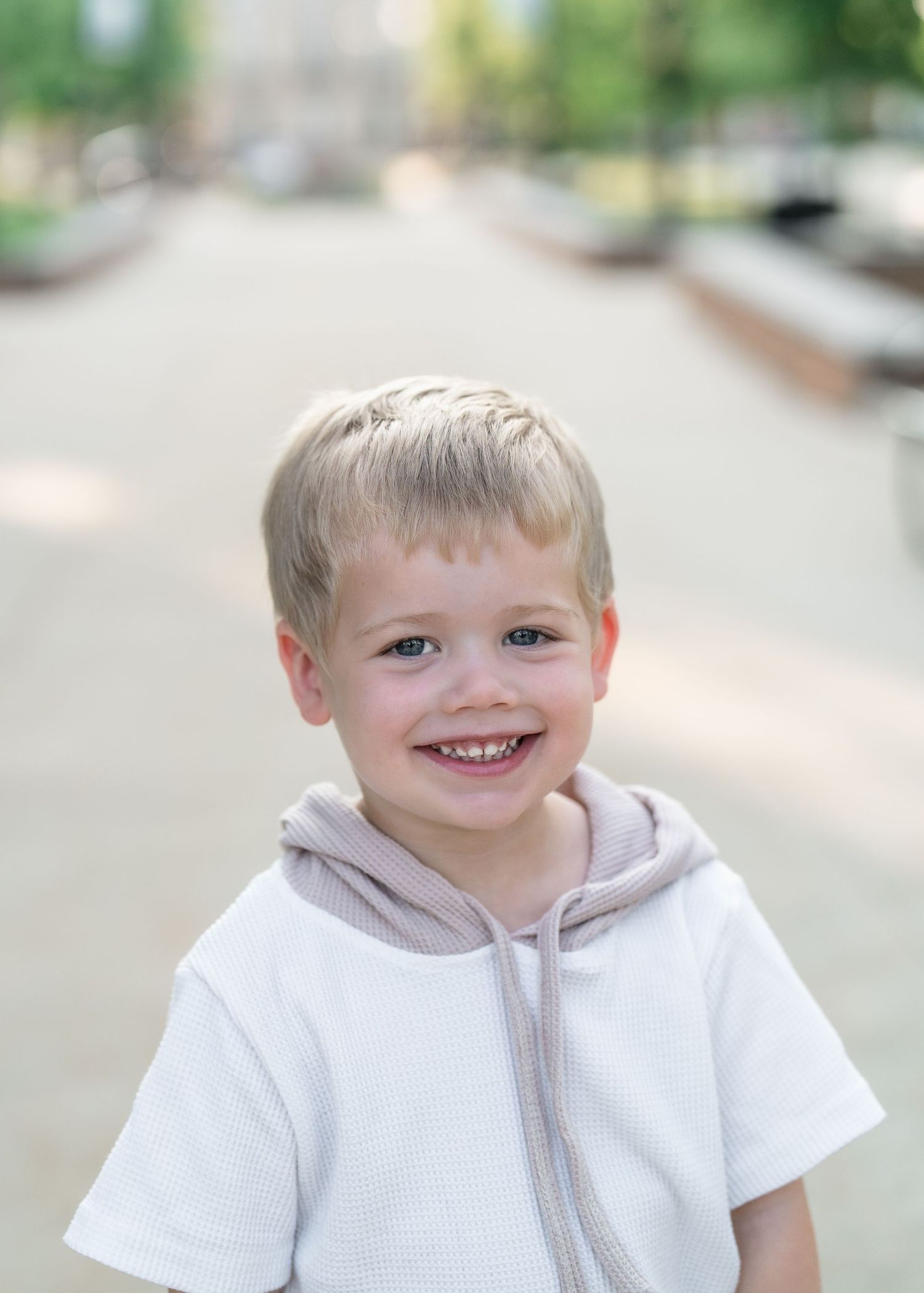 A child wearing a white shirt and brown pants poses in a sequence of playful expressions against a light background in Downtown CFalls, Ohio