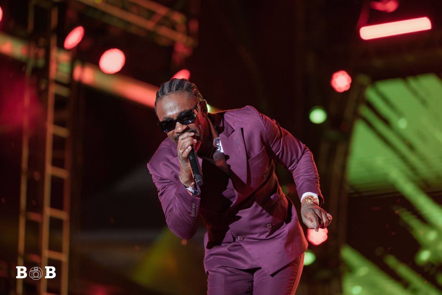 Christopher Martin live at the St. Kitts Music Festival 2025, wearing a maroon suit and sunglasses, with stage lights glowing behind him.