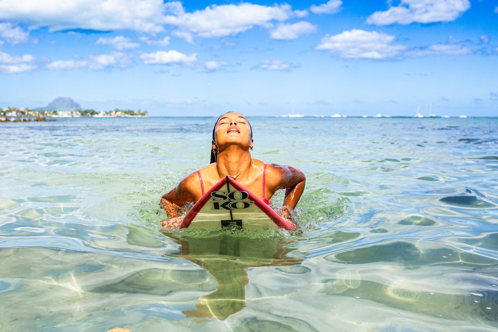 a surfeur girl in the sea with her surfboard after a duckdive with blue sky and turquoise sea