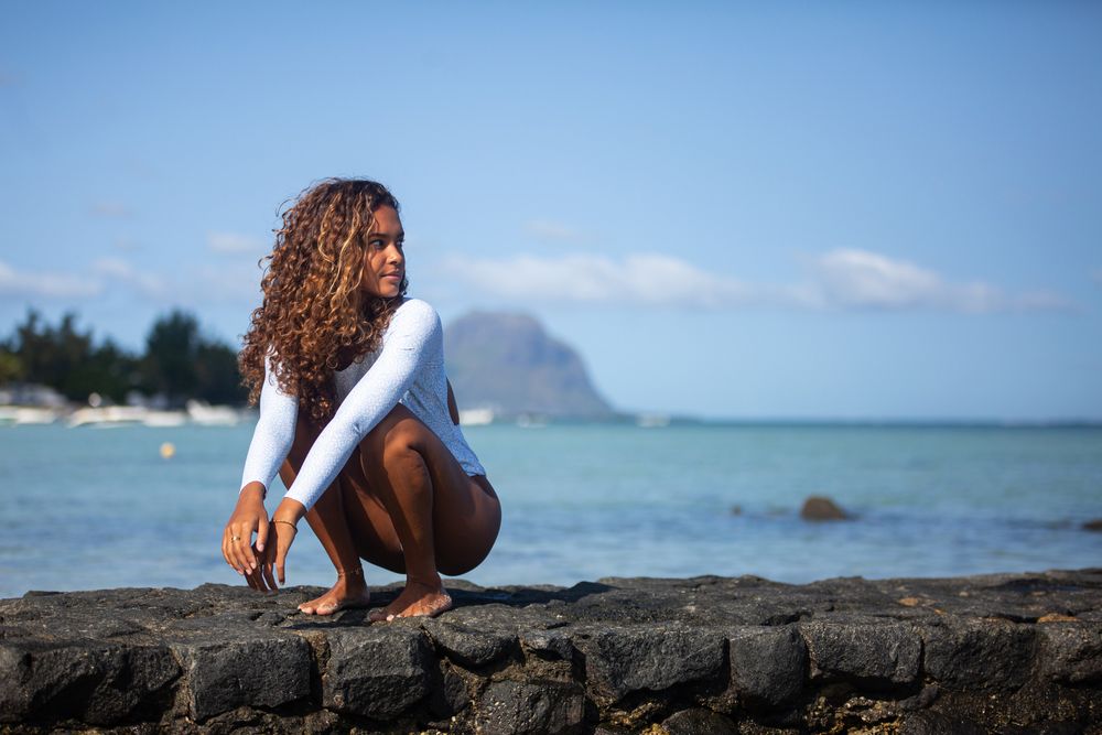 a girl posing in bikini at the beach with le Morne mountain behind her Mauritius photographer. Wedding photographer. Wedding in Mauritius.
