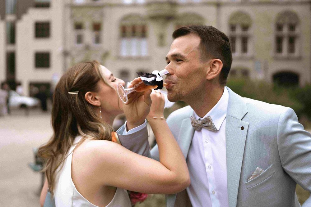 A joyful wedding moment captured in front of elegant architecture with a tender gesture.