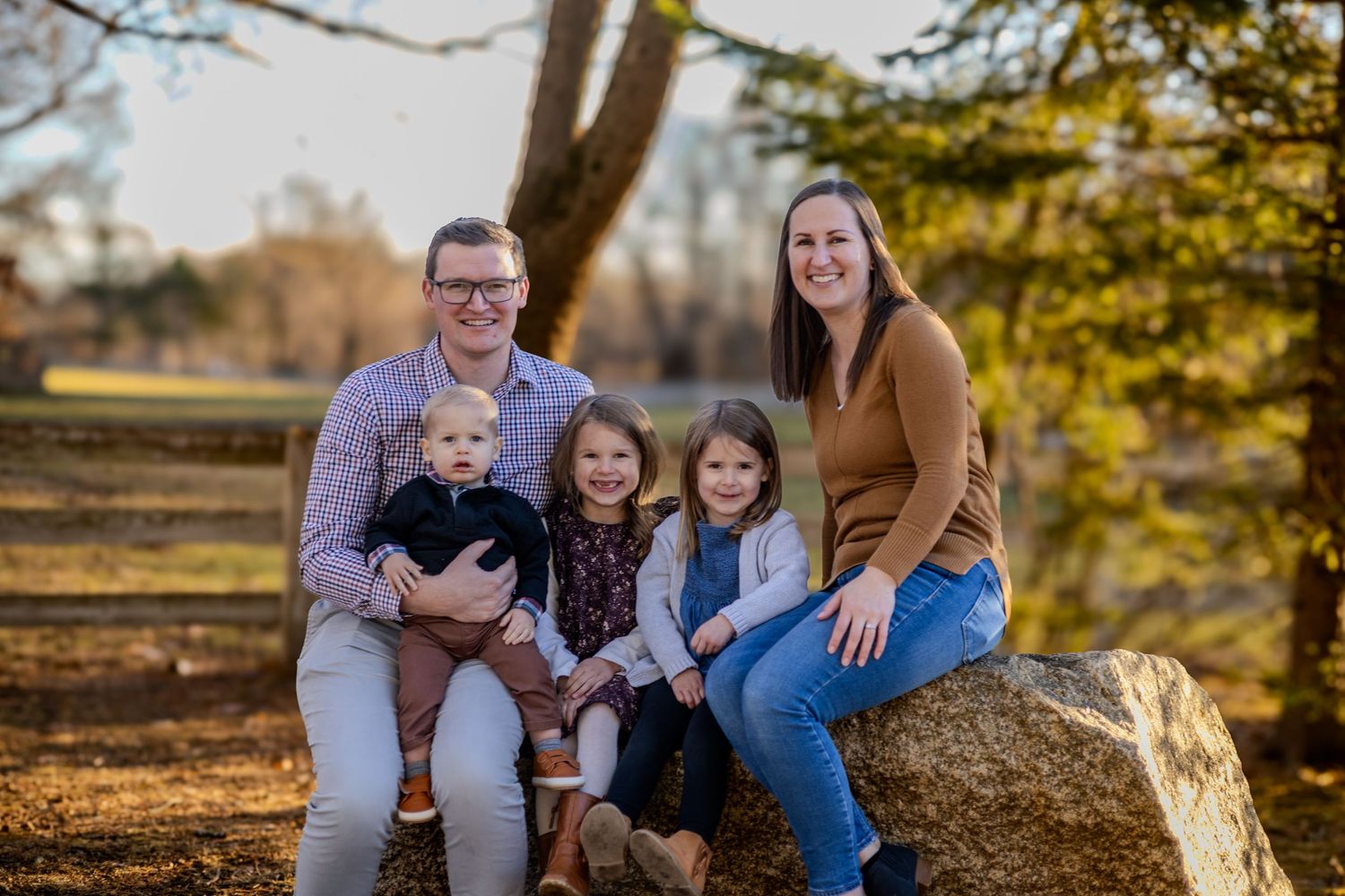Family portraits captured outdoors during golden hour autumn photoshoot with fall foliage in the background.