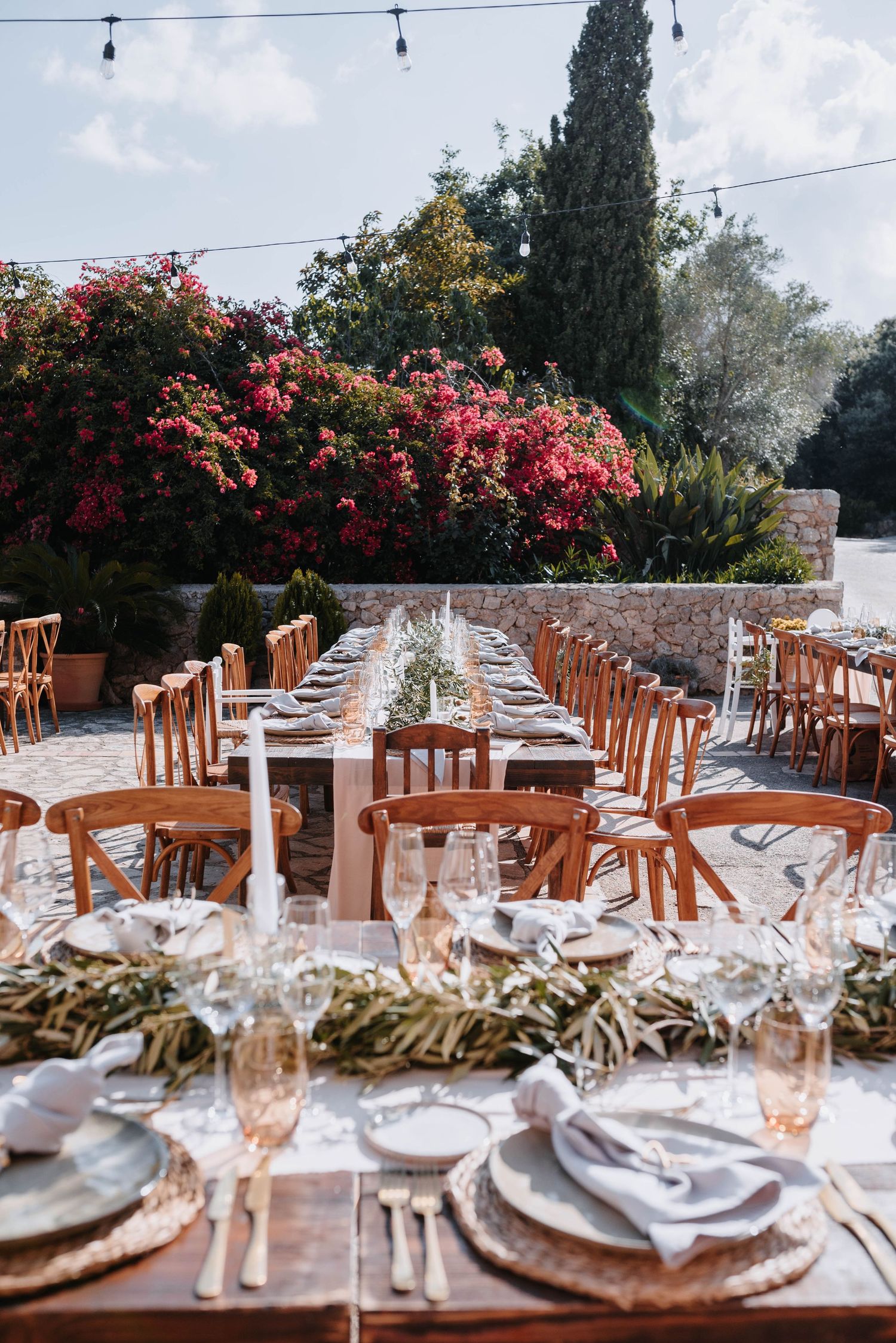 Dinner Dekoration einer Hochzeit auf der Finca Xiclati auf Mallorca. mit Holztafeln, hellen Tischläufer, Kerzen, Gläser und Olivenzweigen.
