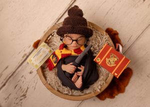 Newborn dressed in Harry Potter themed costume with books and accessories.