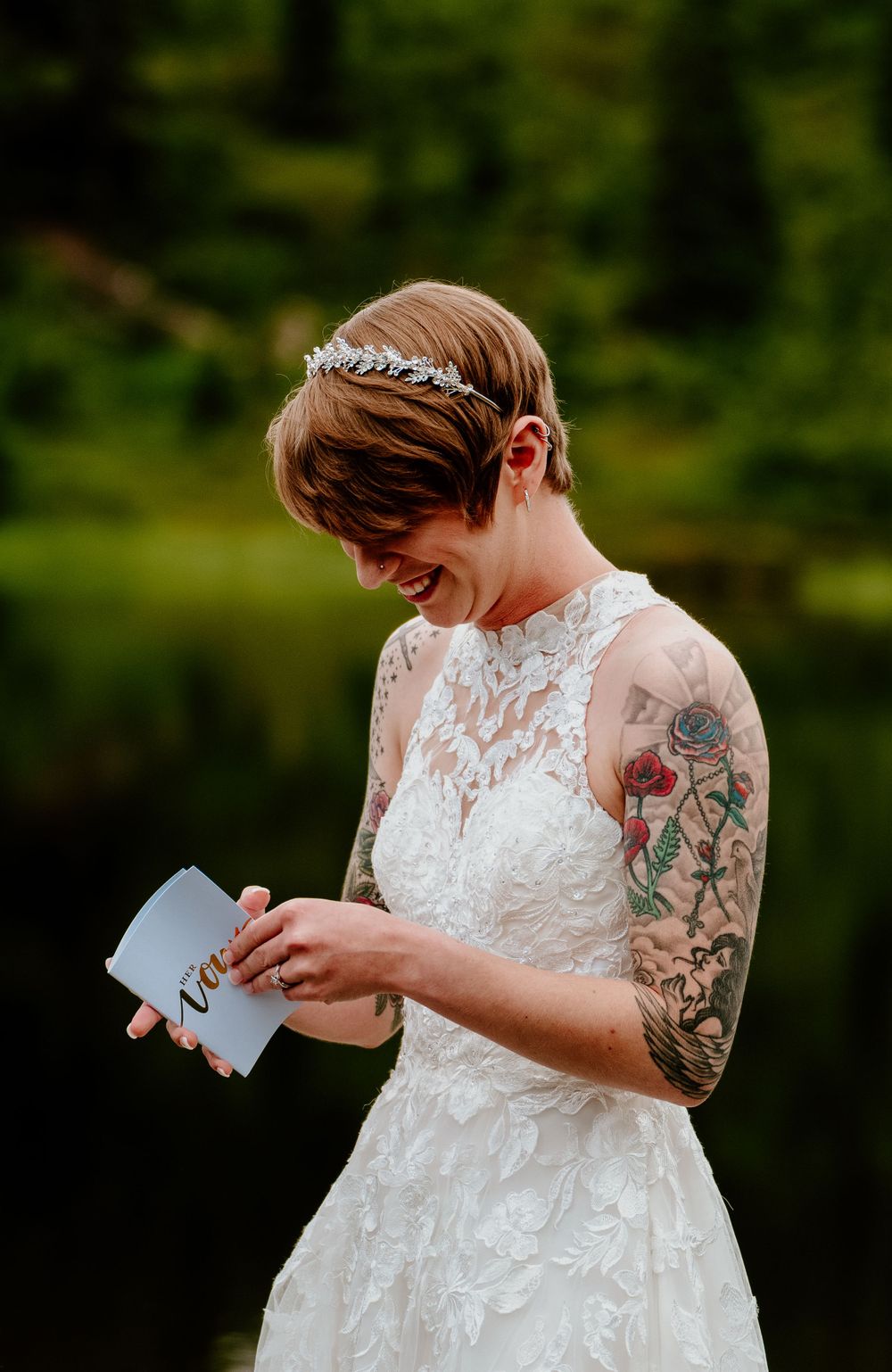Reading an emotional letter outdoors while wearing a white lace wedding gown.