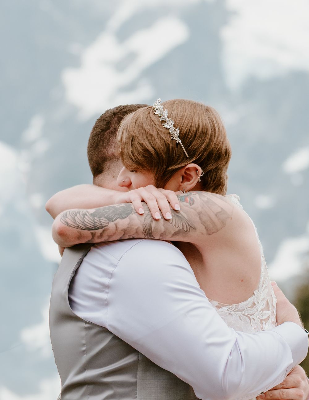 Emotional embrace during mountain wedding with snow-capped peaks in background.