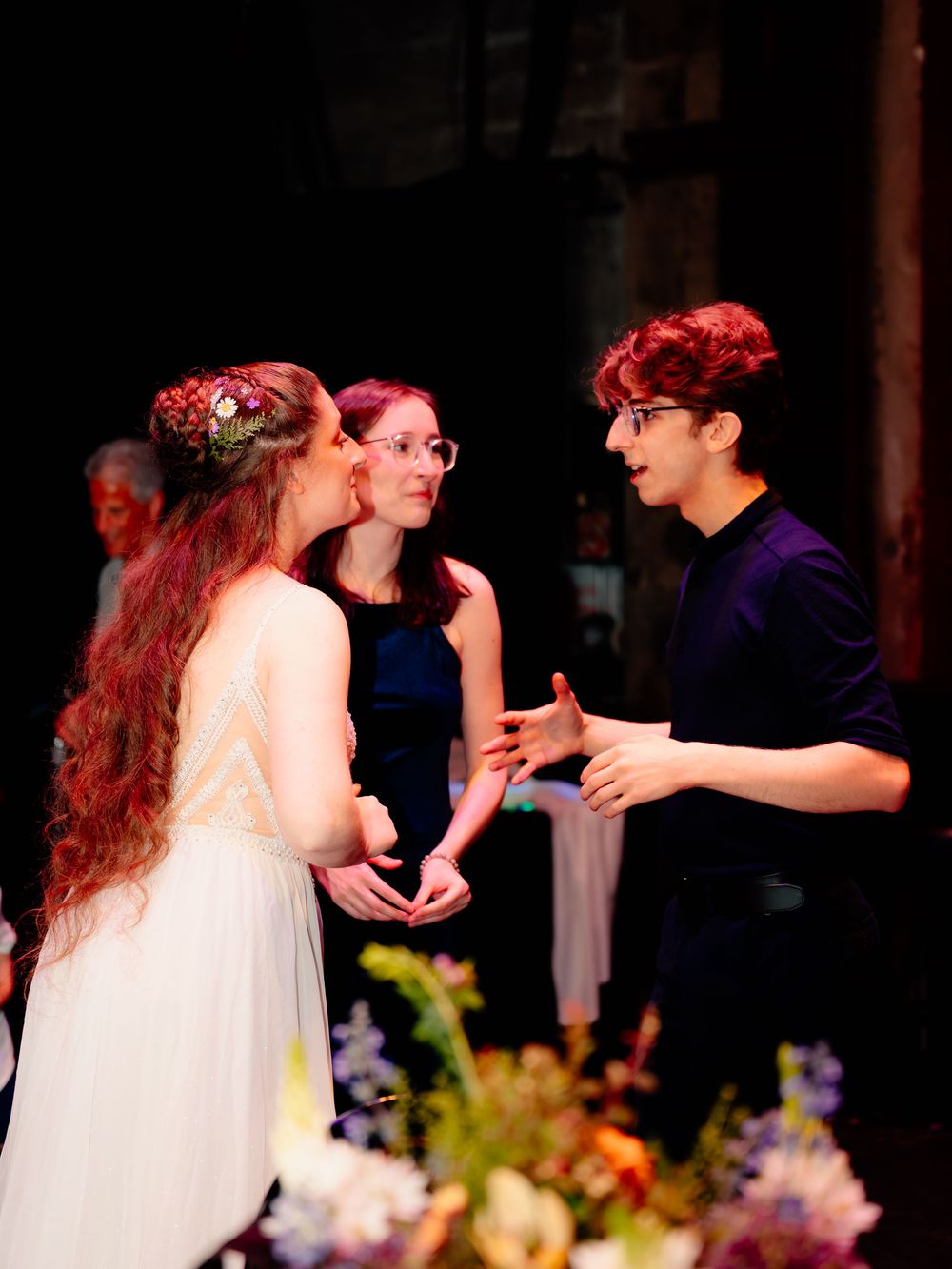 An animated conversation between wedding guests surrounded by floral decorations.