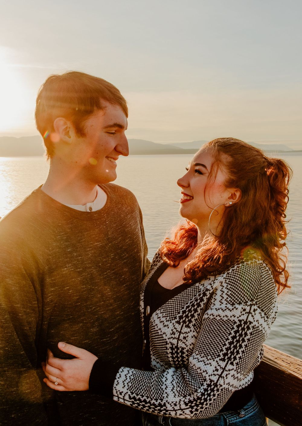 Sunset engagement photos showing romantic couple embracing by waterfront in golden light.