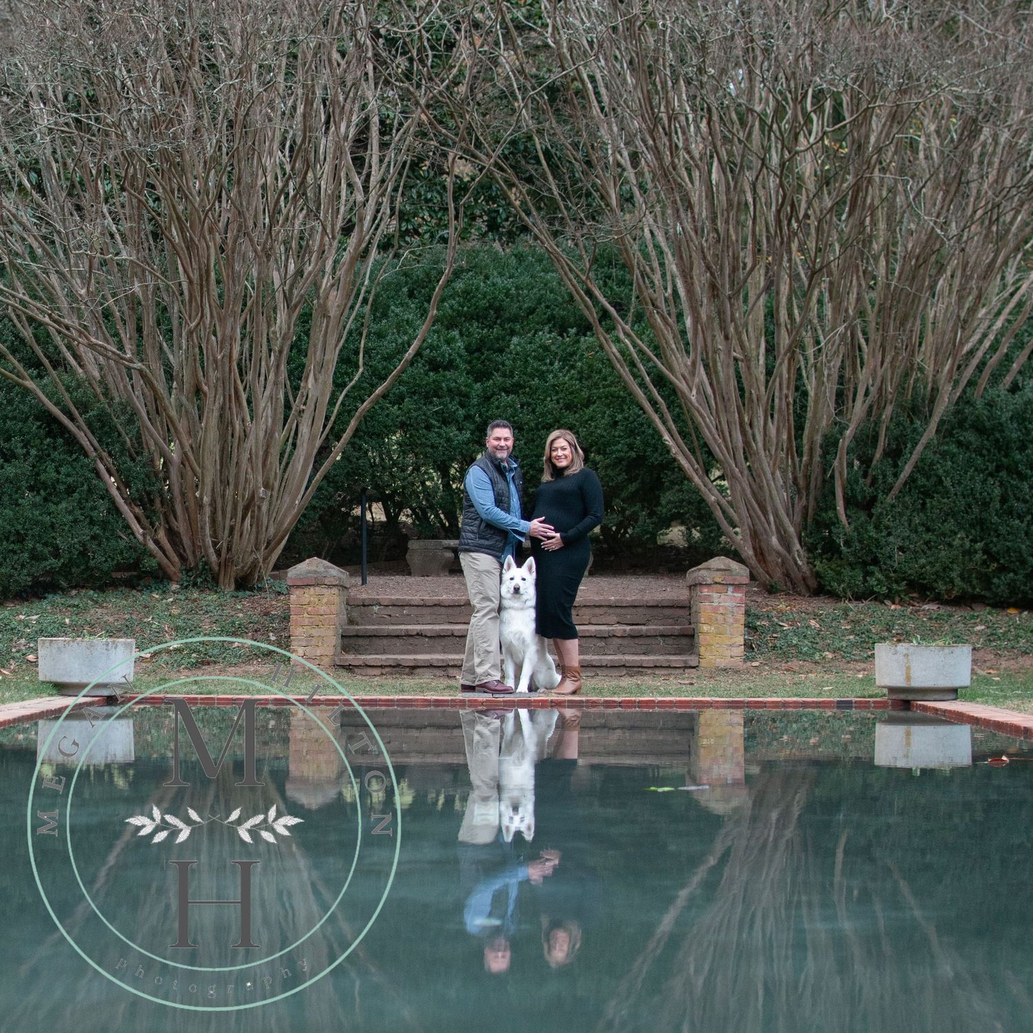 Maternity photo of a couple and dog posed by the reflecting pool at Morven Park
