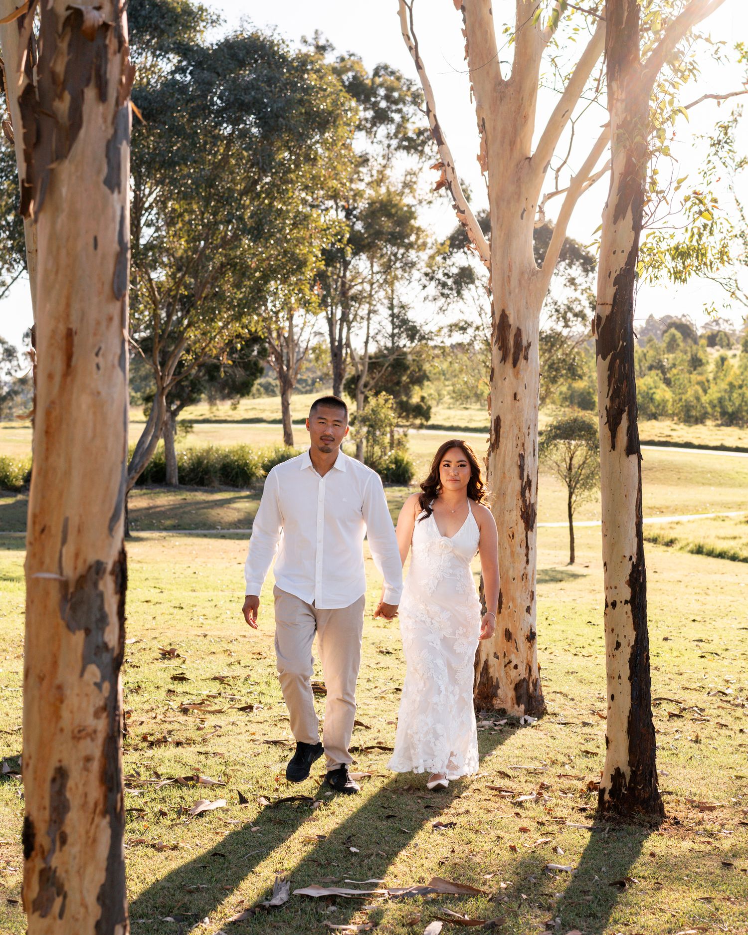 Couple walking towards the camera during a photoshoot in western sydney parklands golden hour time
