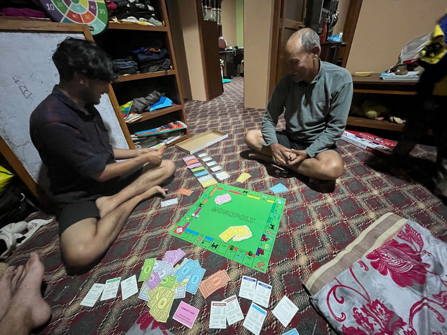 People playing cards and board games on a patterned tablecloth.