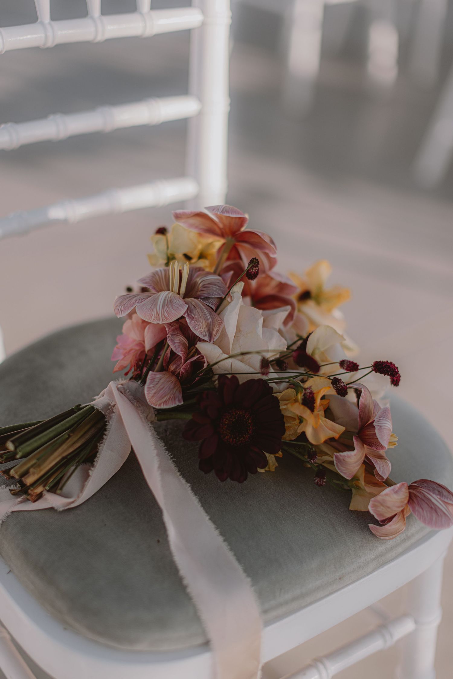 Vintage-style floral bouquet resting on a white chair with soft natural lighting.