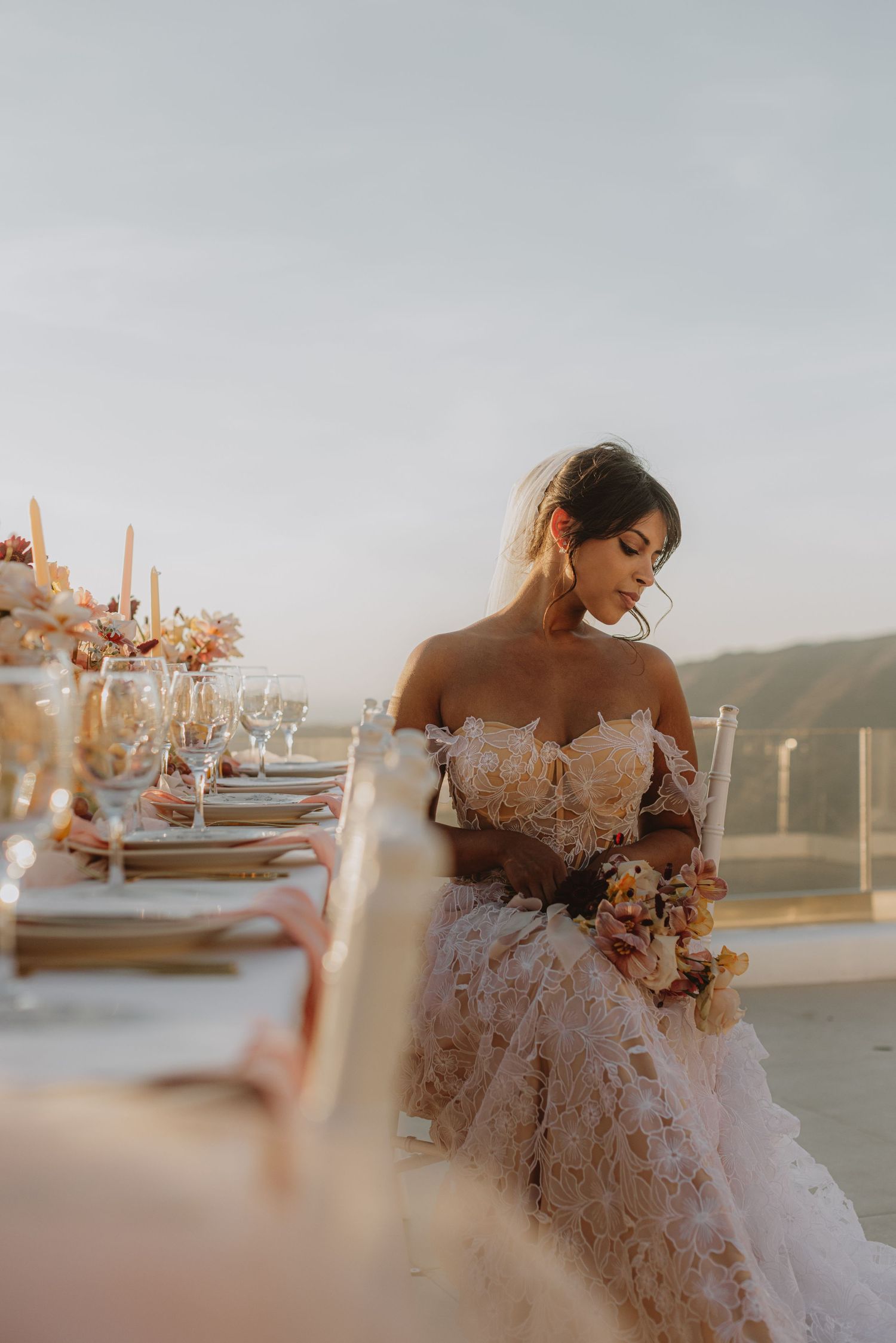 Elegant table setting with floral arrangements and place settings overlooking a coastal view.
