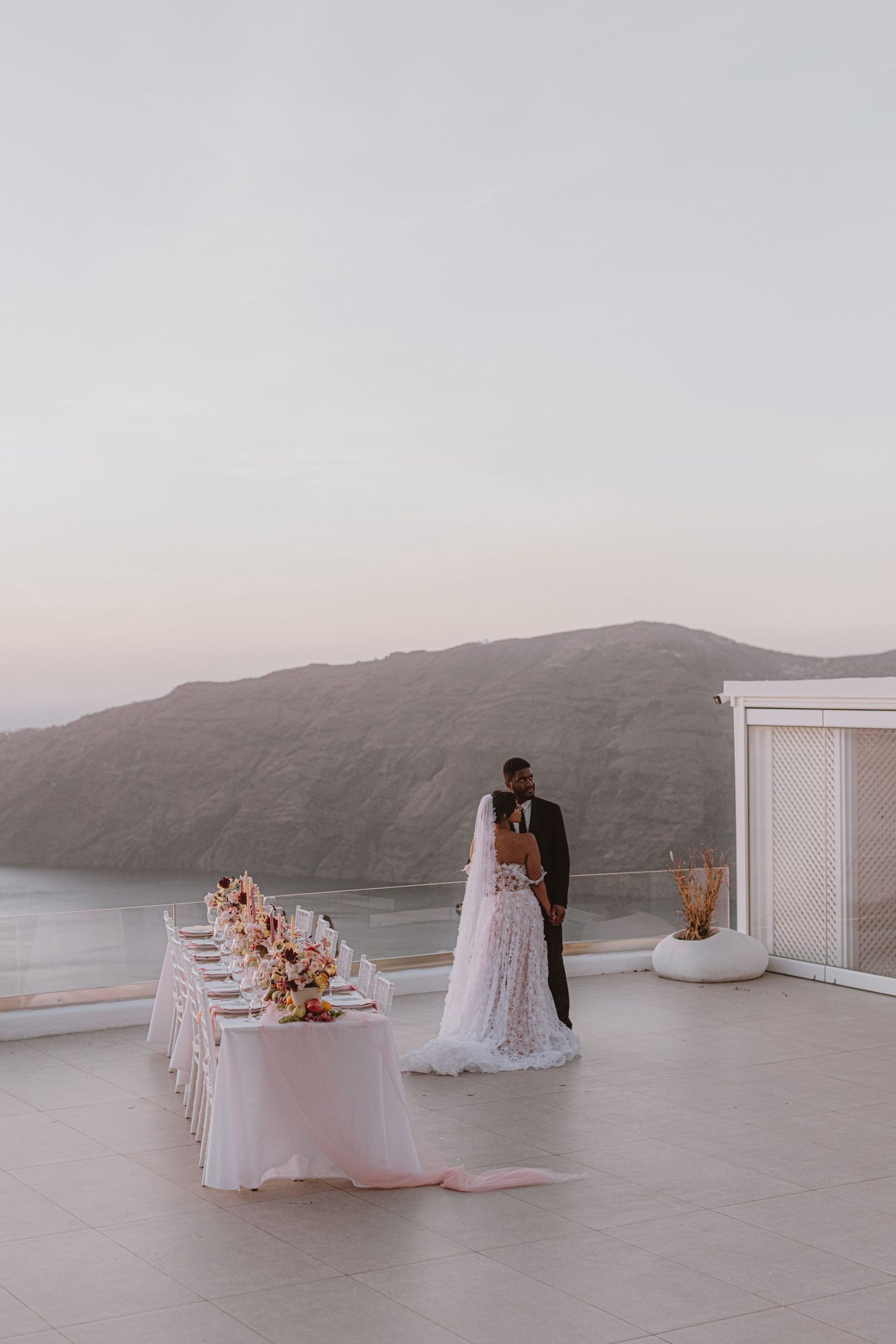 Minimalist white wedding reception venue with mountain views and elegant table settings.