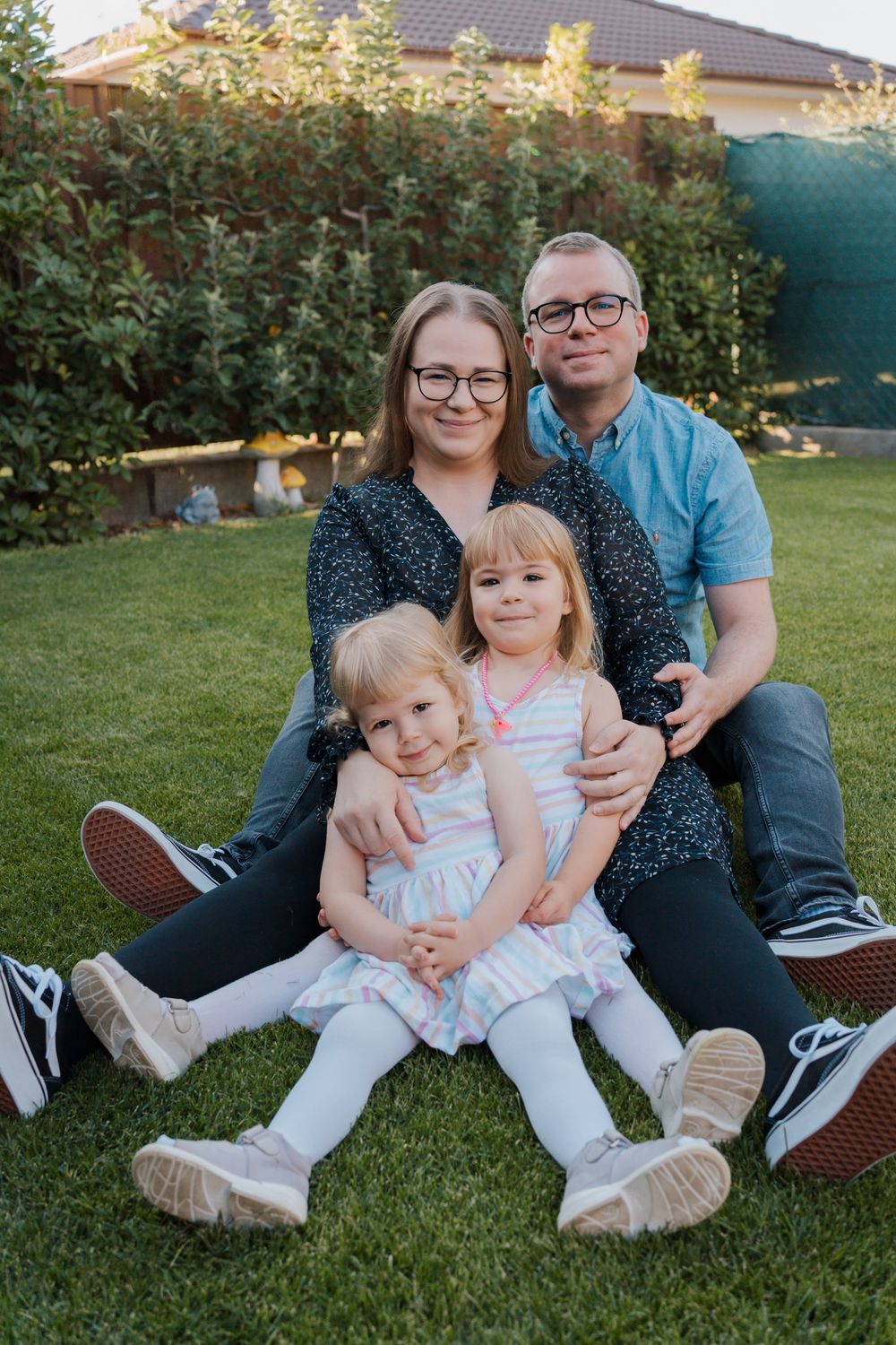 Family sit together on green grass in a backyard setting during golden hour lighting for their in home family photoshoot in Rouse Hill