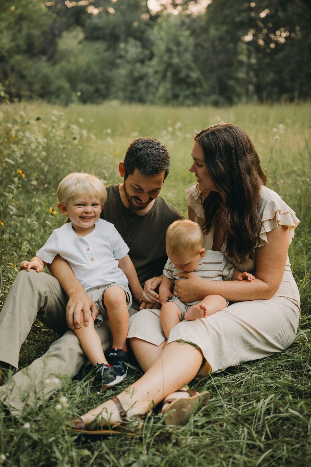 Family sitting together in a sunny meadow with wildflowers on a summer afternoon.