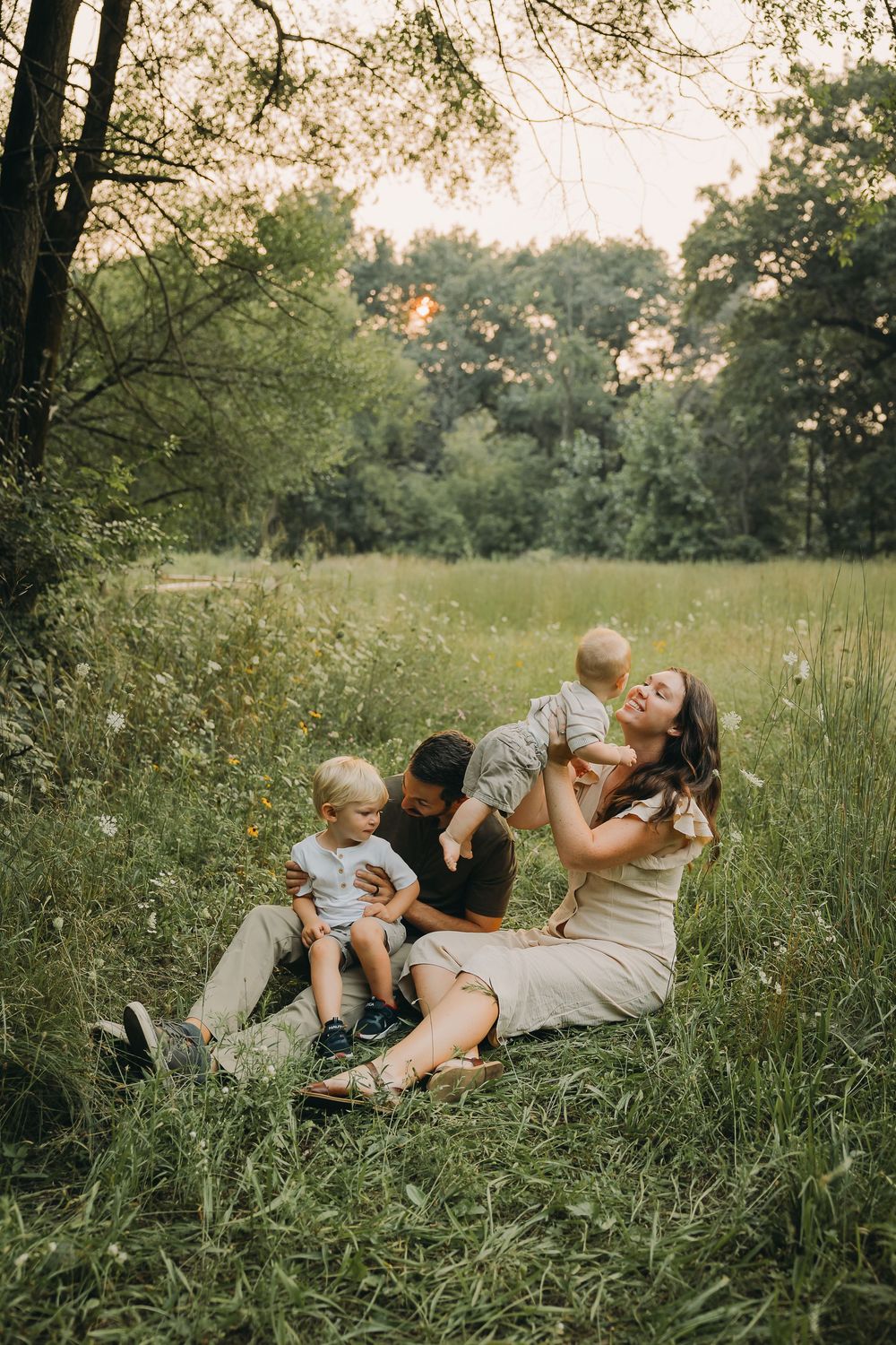A tender moment shared between a family relaxing together in a sunlit meadow on a warm summer evening.