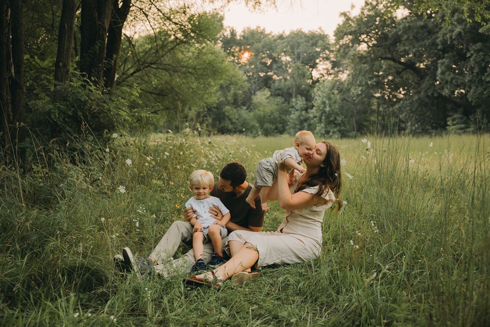A romantic couple shares tender moments together while lying in a grassy meadow at sunset.