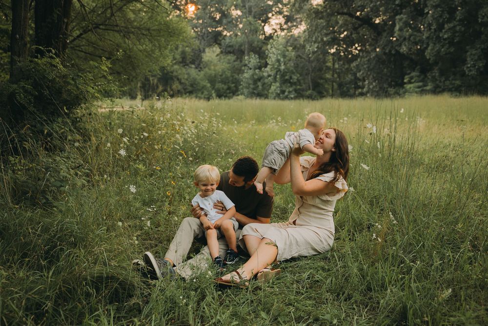 Family members lay together in a grassy meadow during a warm summer afternoon.