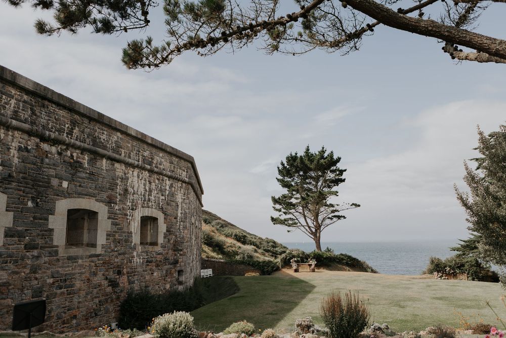 Scenic coastal stone building with lone tree overlooking the sea on a wedding day.