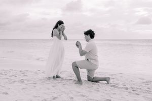 Series of black and white photos showing a surprise beach proposal on white sand.