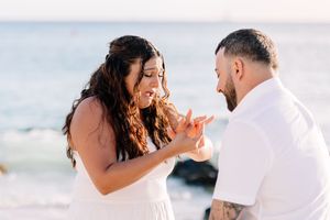 Candid beach wedding moments captured during sunset with couple in white attire.