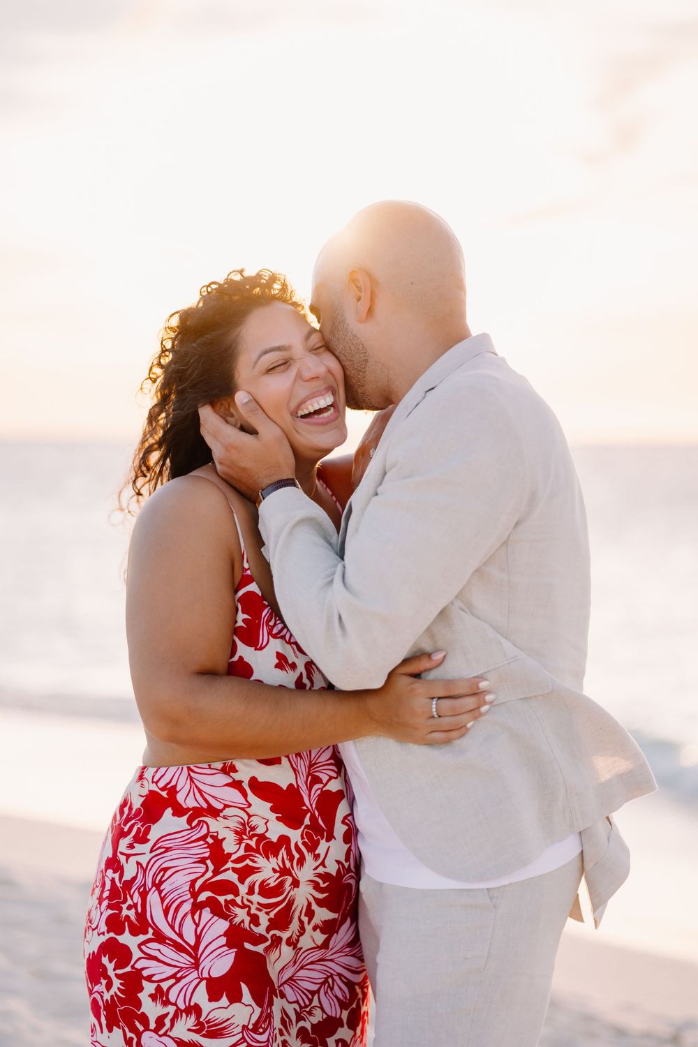 Joyful couple sharing intimate moment on beach during sunset.