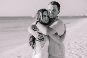 Black and white photo capturing an intimate moment between a couple on the beach.