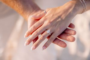 Close-up detail of hands with engagement ring in warm sunlight.
