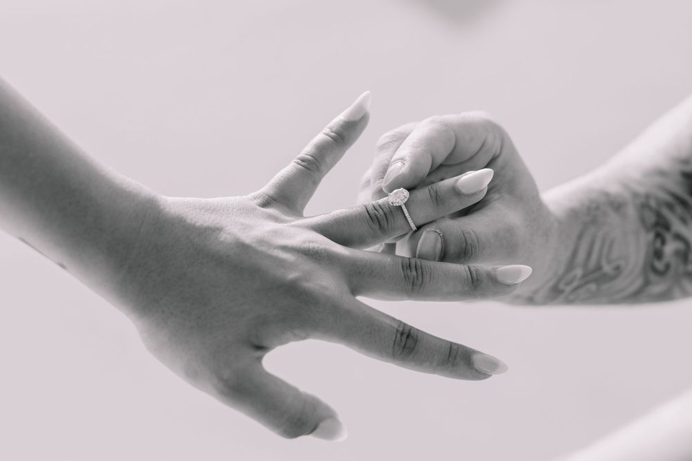 Black and white close-up of hands with wedding rings in artistic composition.