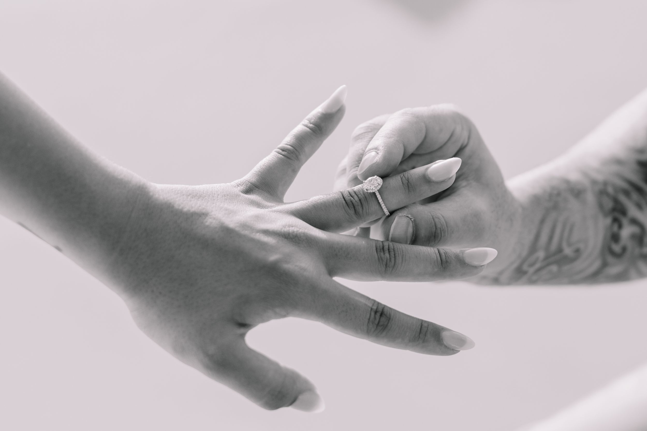 Black and white close-up of hands with wedding rings in artistic composition.