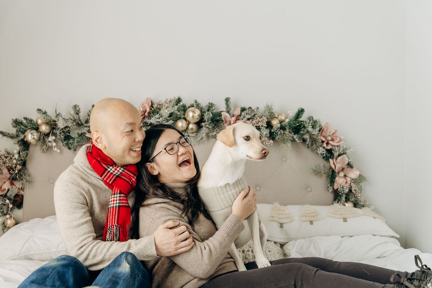 A couple in winter attire shares tender moments while posing against a floral backdrop during a photo session. christmas minis 2025