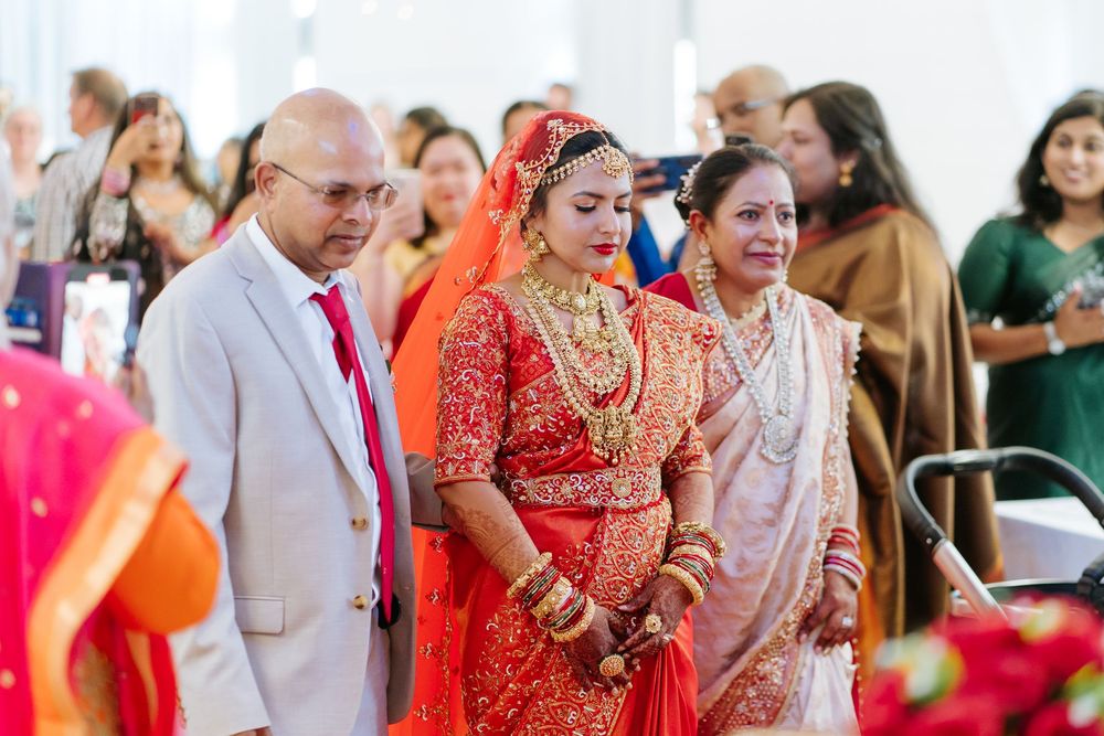 A wedding ceremony featuring guests in traditional Indian attire including a bright red bridal sari.