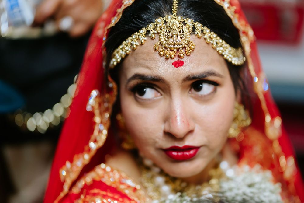 Traditional Indian bride wearing ornate gold jewelry and red attire with bindi and wedding makeup.