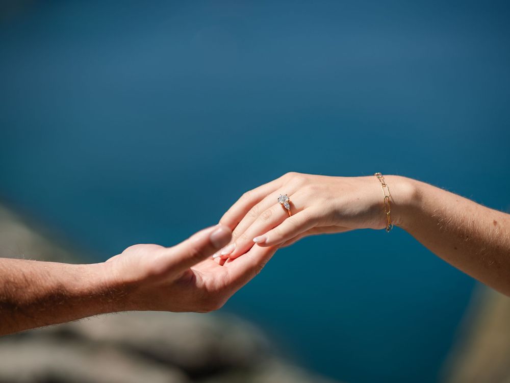 Two hands reaching towards each other against a deep blue background in an artistic pose.