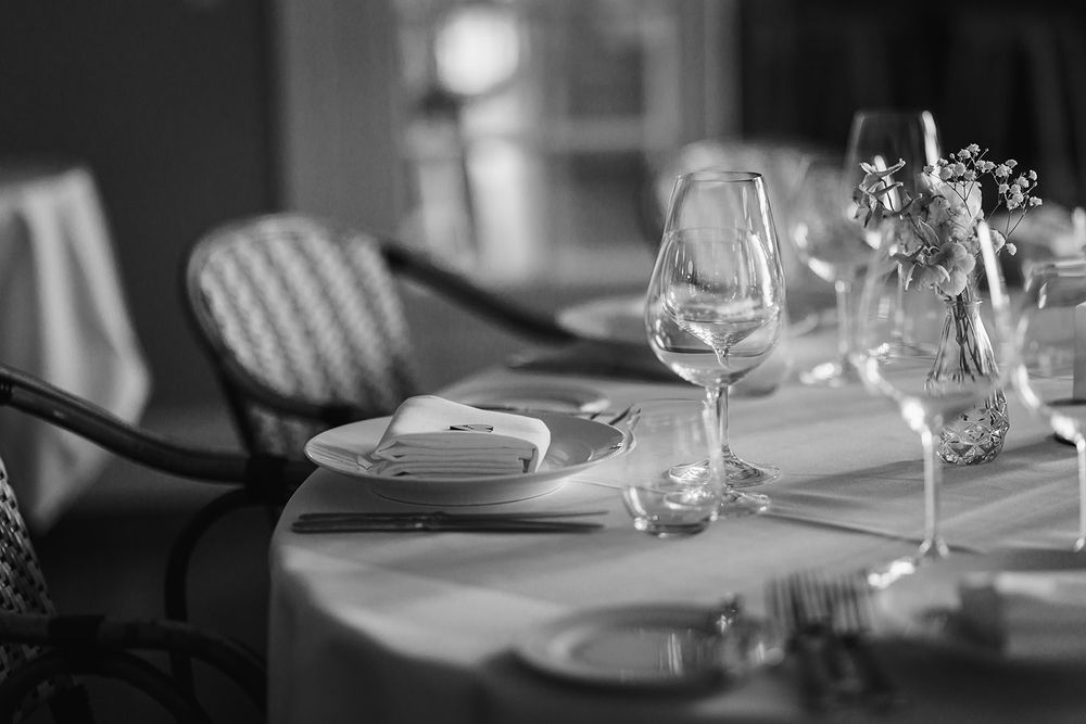 Empty wine glasses and place settings arranged on a formal dining table in a dimly lit restaurant setting.