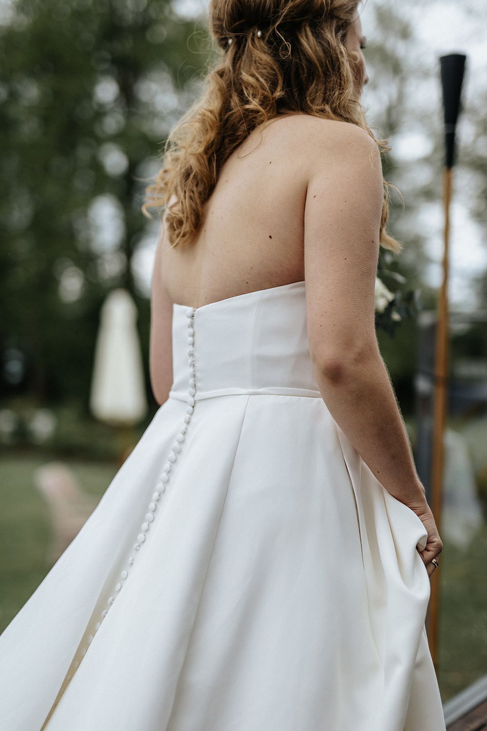 Close-up details of an elegant white wedding dress with delicate button closures along the back.