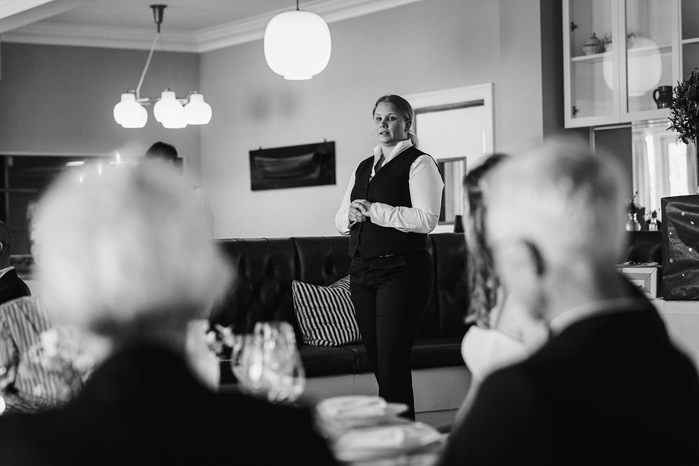 A black and white photo montage shows people gathered in an indoor setting with pendant lights hanging from above.