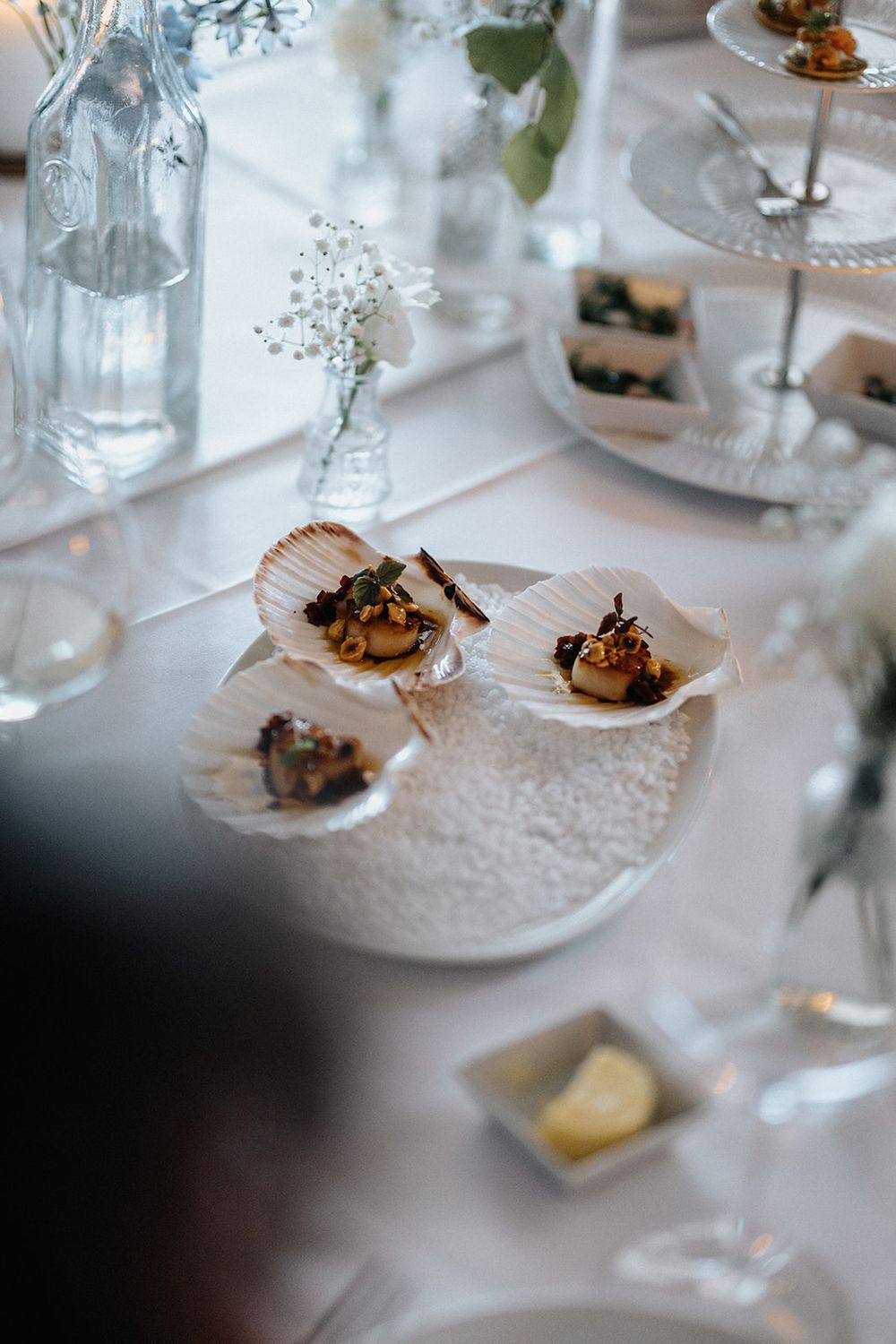 Close-up view of elegant appetizers served on small plates at a wedding reception with white table linens.