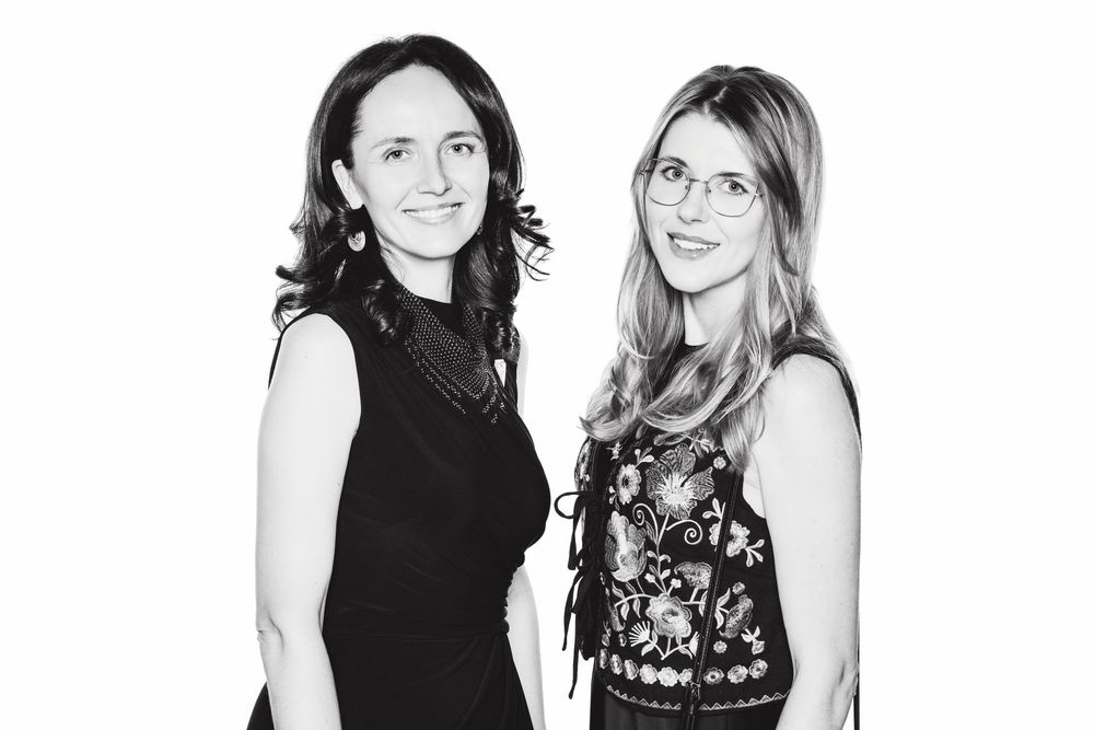 Black and white photograph of two women smiling and posing together at an event.