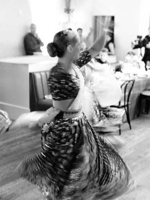 A black and white photo of a dancer twirling in a patterned dress during a performance.
