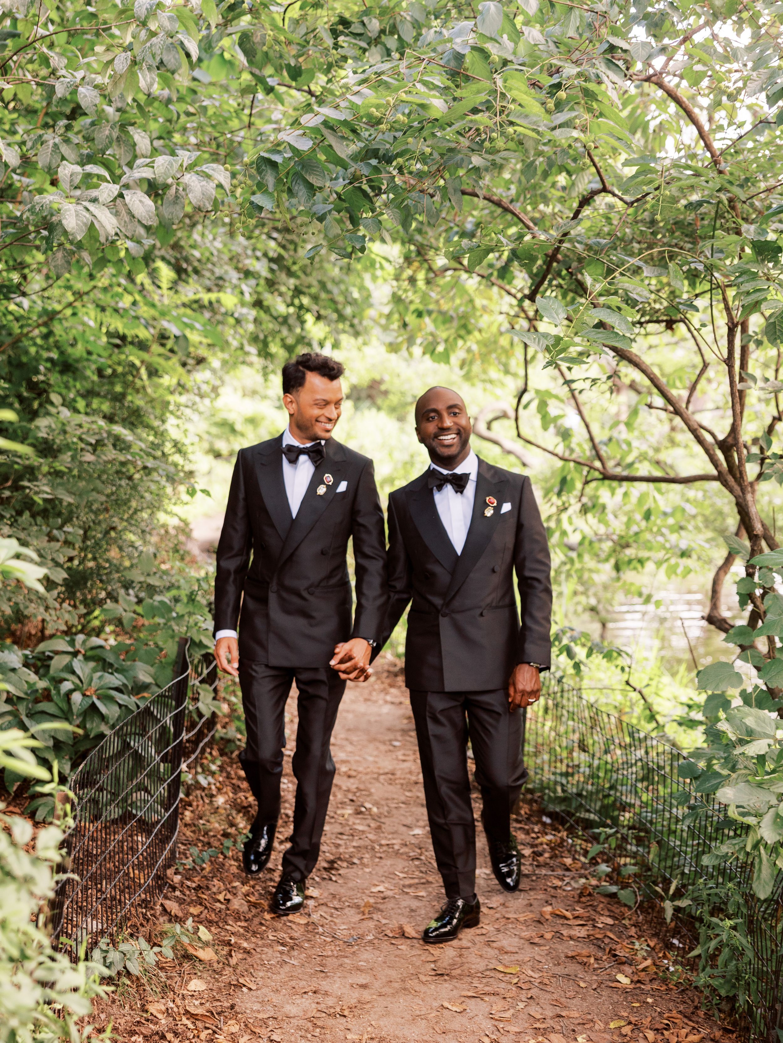 Wedding party members stroll along a peaceful garden path surrounded by lush greenery.