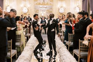 Wedding celebration in an opulent ballroom with crystal chandeliers and gold decor.