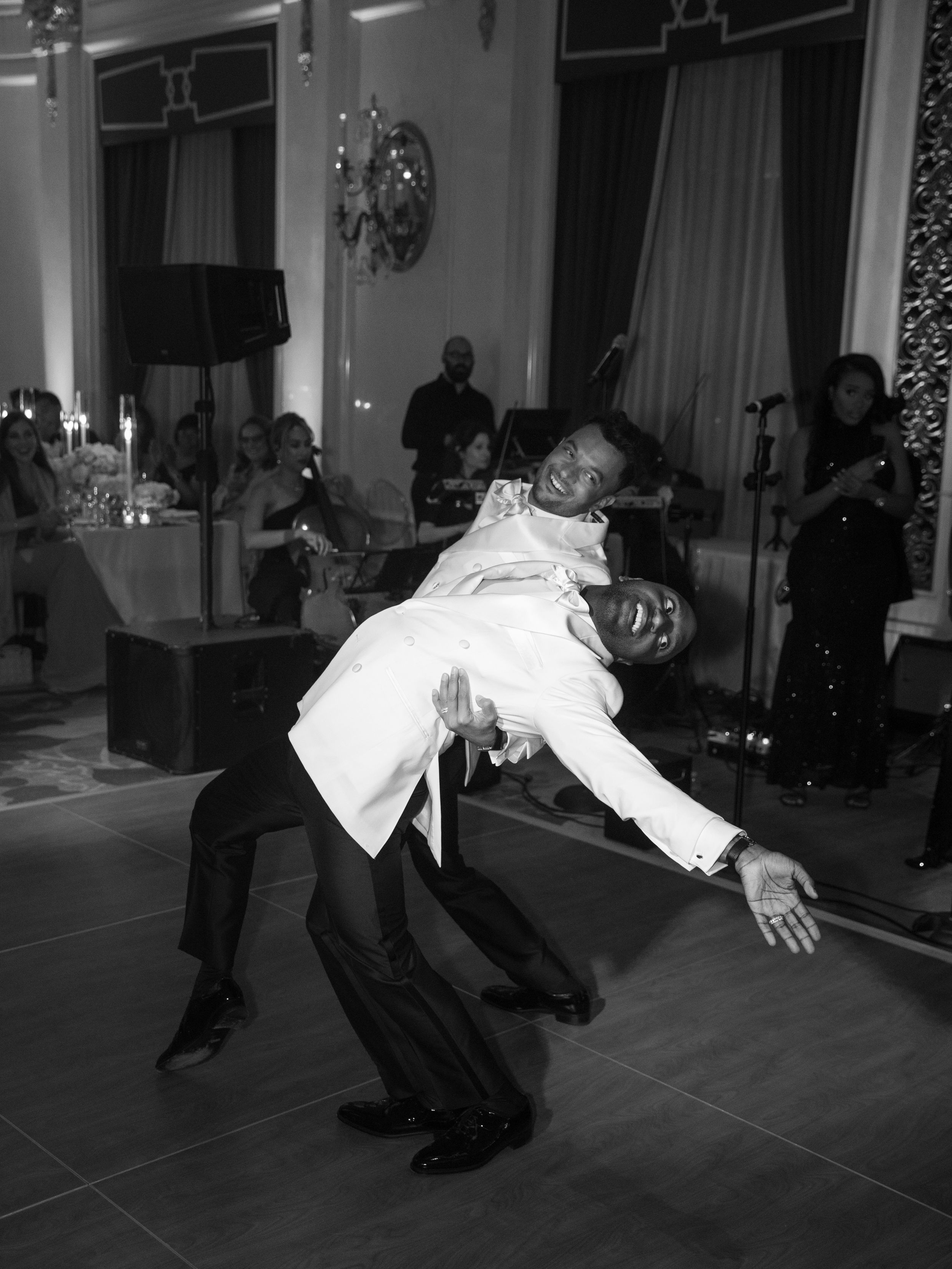 Wedding guests perform energetic dance moves on the reception dance floor.