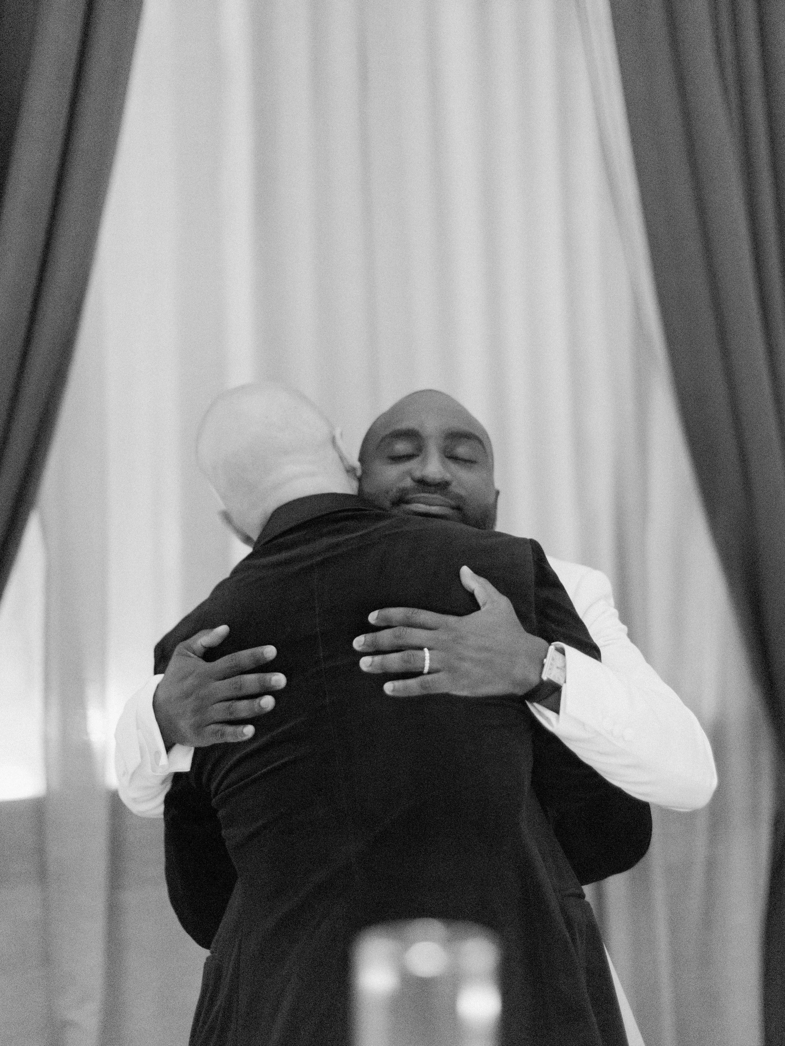 Two people share an emotional embrace during a touching wedding moment.