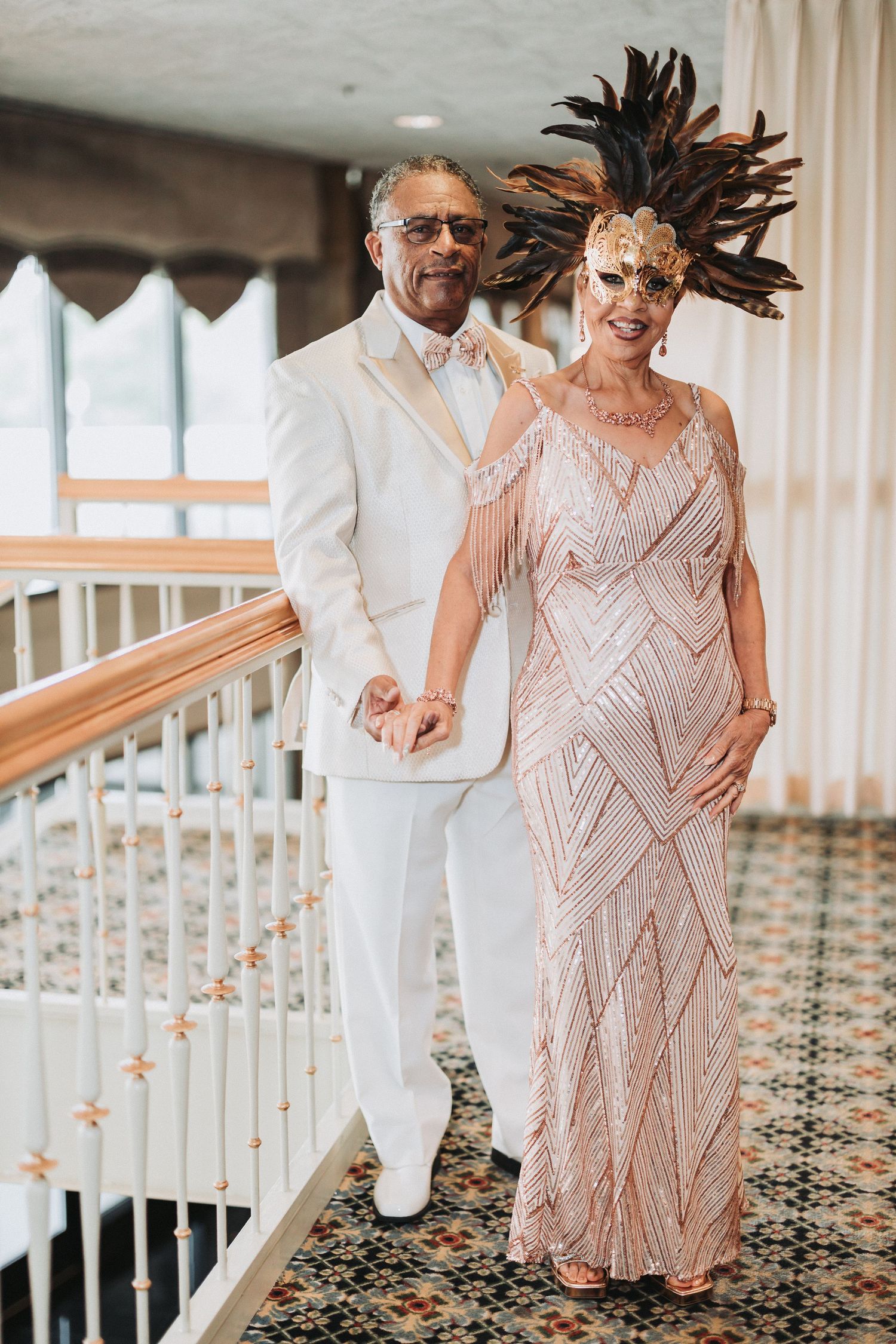 A couple dancing together on patterned carpet, with one person wearing white and the other in a sparkly blush gown.