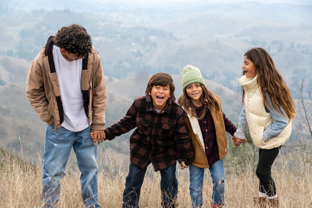 Group enjoying a playful moment together on a hillside with mountains in the background.